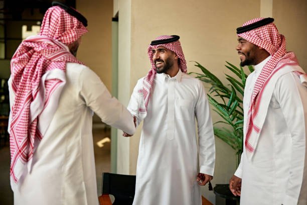Riyadh businessmen in 20s and 40s standing and greeting one another as they meet to discuss project development and collaboration.